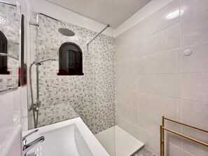 Bathroom features a large bathtub, shower area, and mosaic tile walls.