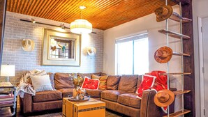 Ein Wohnzimmer mit einem braunen Ledersofa, einem Holztisch und einer Ziegelwand.
