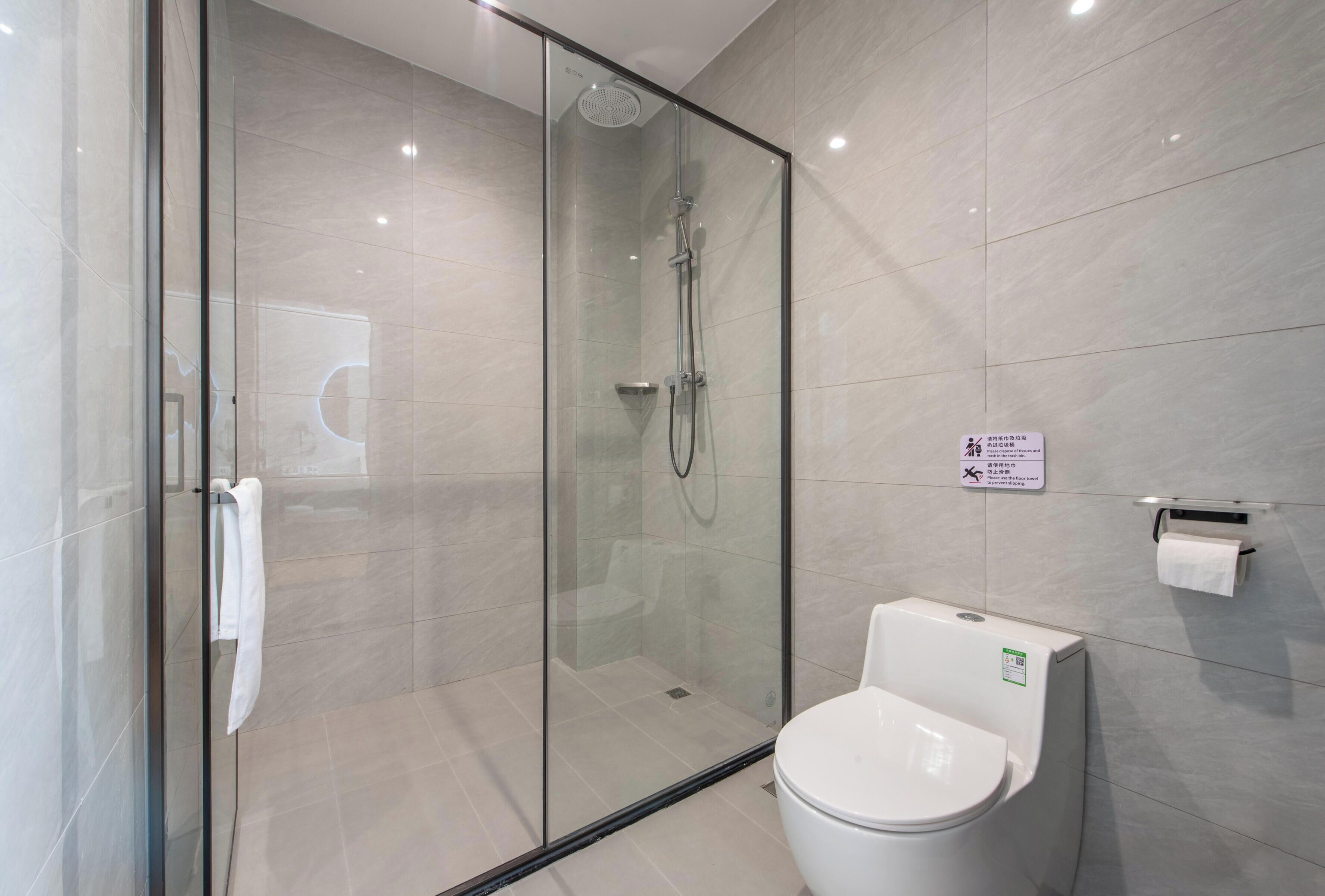 A modern bathroom with a glass-enclosed shower, a toilet, and a towel rack.