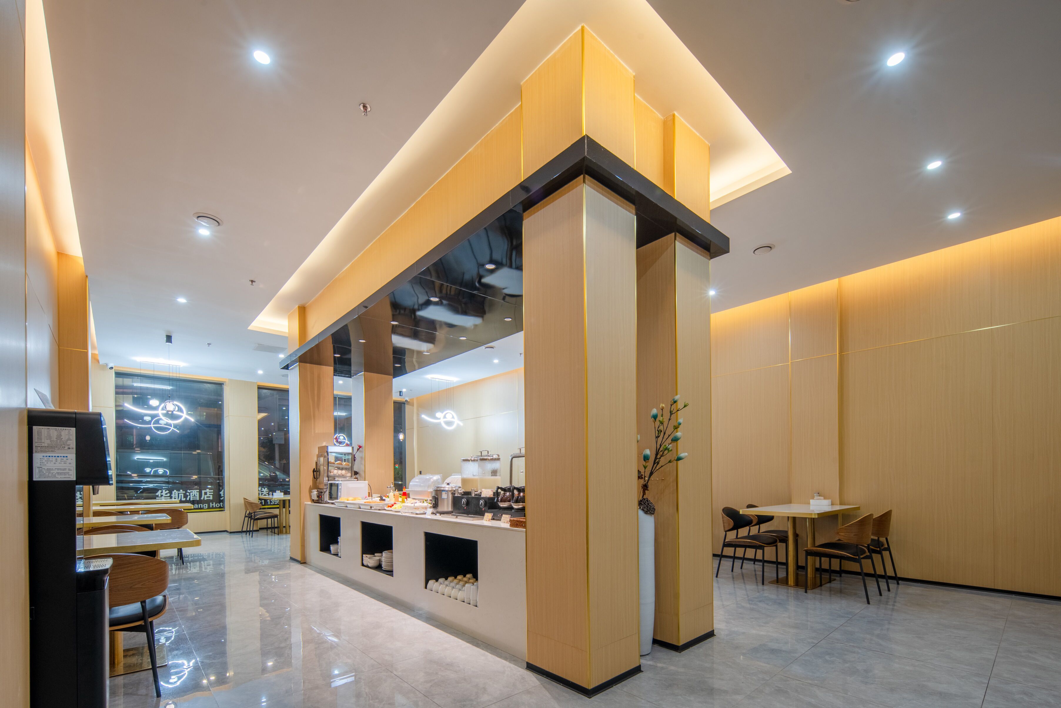 A modern hotel lobby with a reception desk, seating area, and a view of the cityscape through large windows.