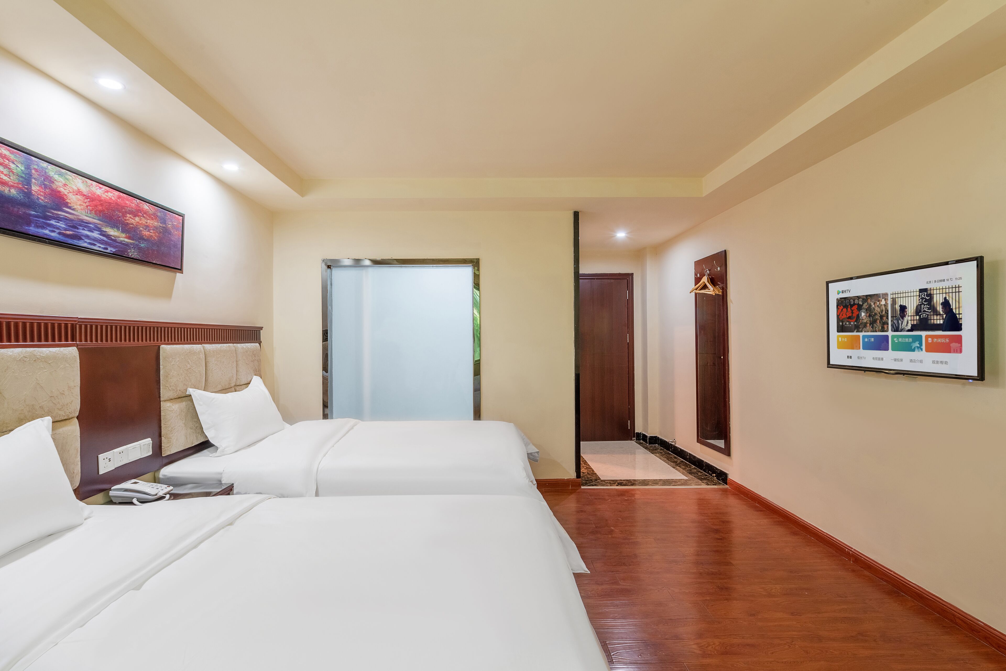 A hotel room with two beds, a large painting, a framed picture, and a wooden floor.