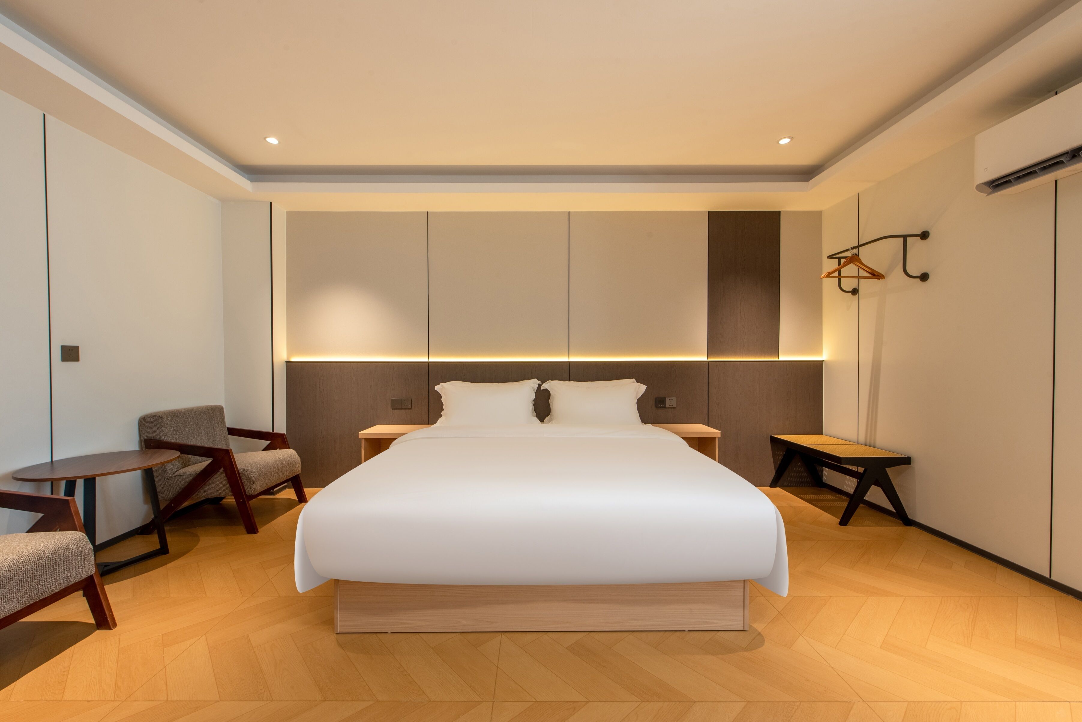 Une chambre d’hôtel moderne avec un grand lit, deux tables de chevet, un petit bureau et une chaise.