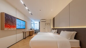 Una habitación de hotel moderna con una cama grande, un escritorio y una televisión instalada en la pared.