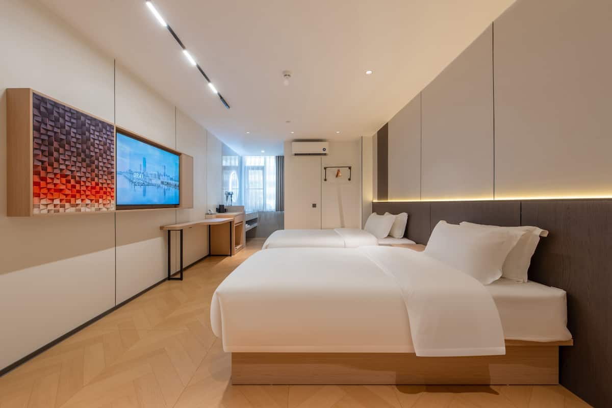 Een moderne hotelkamer met een groot bed, een bureau en een televisie aan de muur.