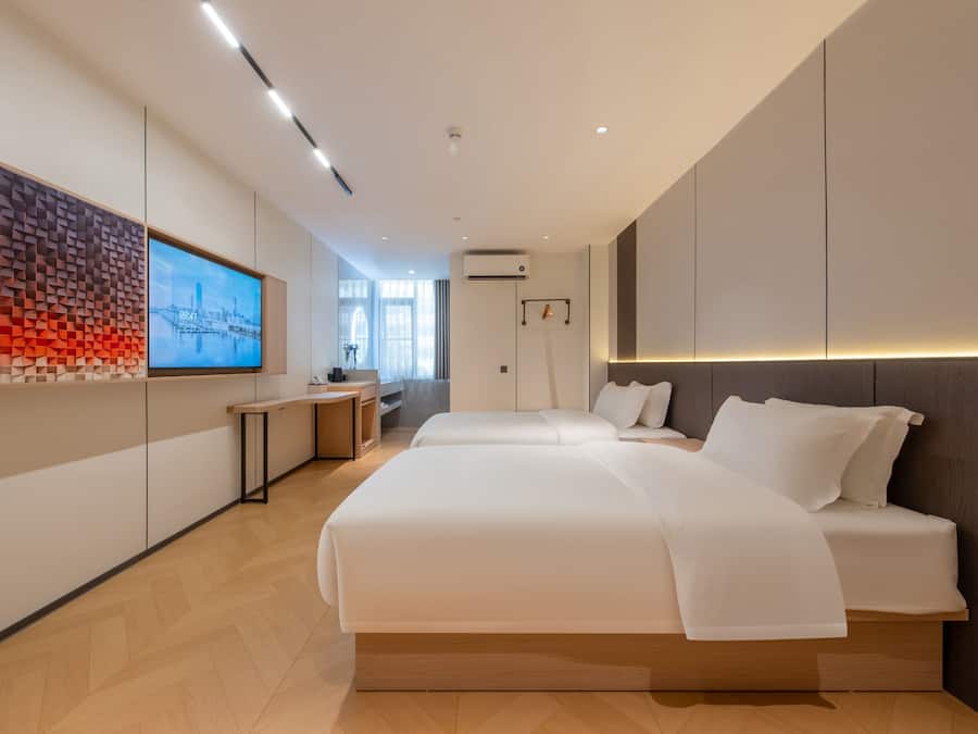 A modern hotel room with a large bed, a desk, and a wall-mounted TV.