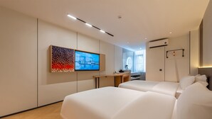 Una habitación de hotel moderna con una cama grande, un escritorio y un televisor montado en la pared.