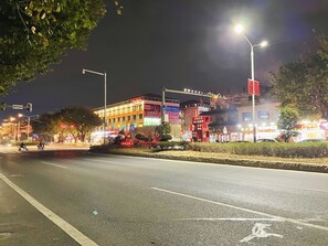 Straatbeeld 's nachts met verlichte gebouwen, straatverlichting en verkeerslichten.