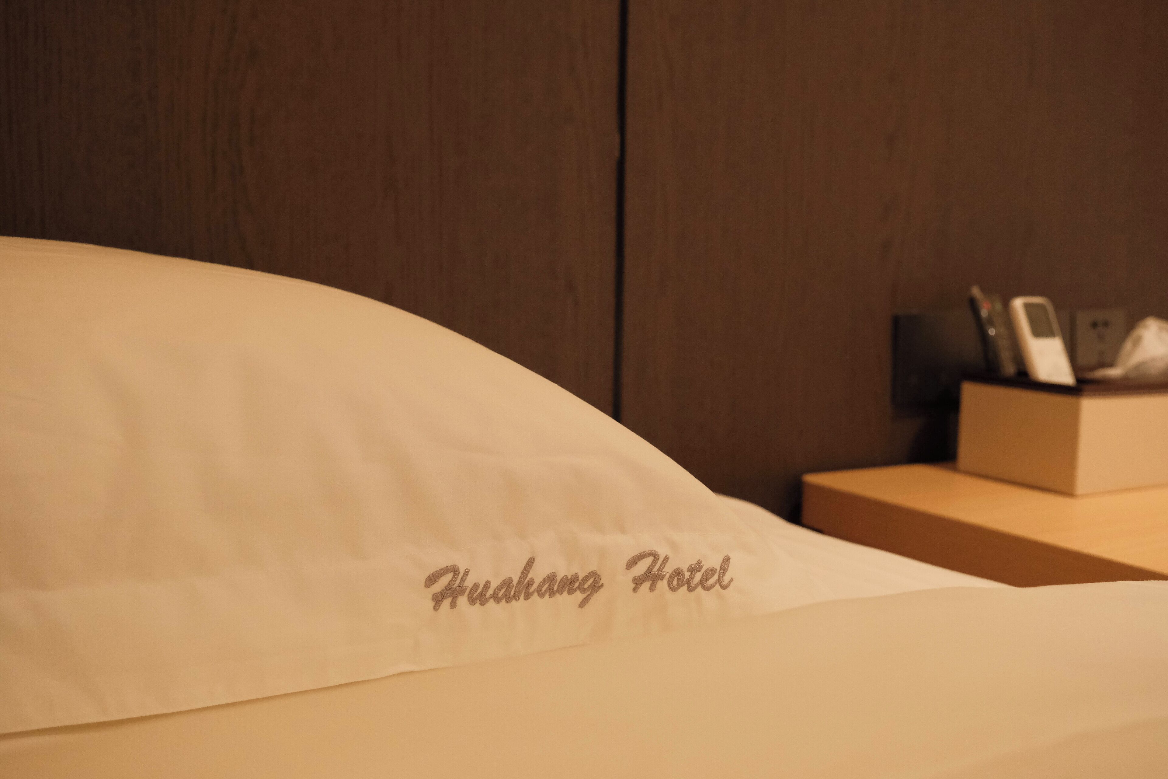 A hotel room with a bed, a nightstand, and a wall-mounted phone.