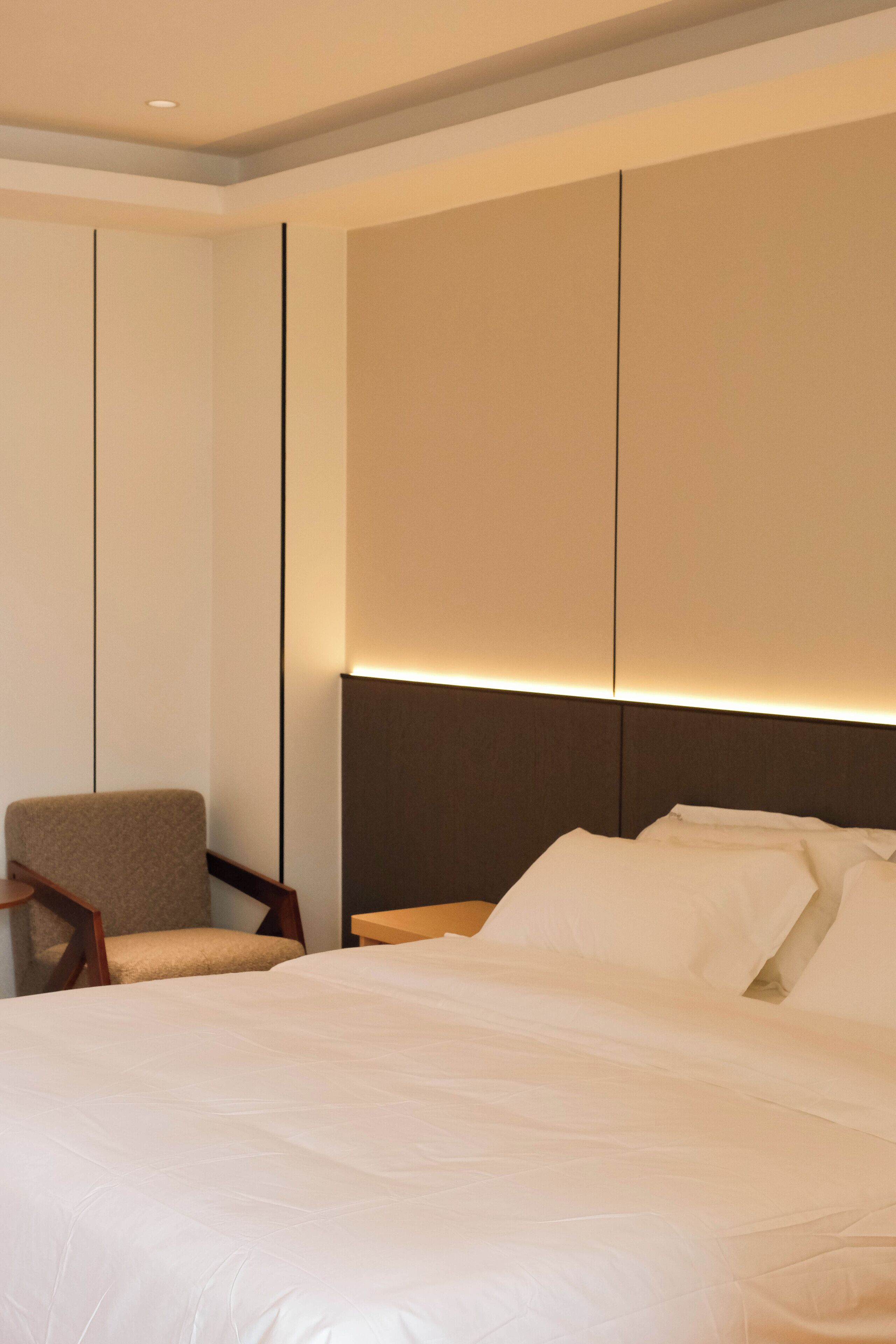 Una habitación de hotel con una cama grande, una silla y un panel decorativo en la pared.