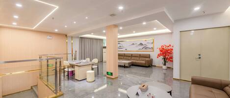 Un moderno vestíbulo de hotel con mostrador de recepción, zona de estar y una escalera.