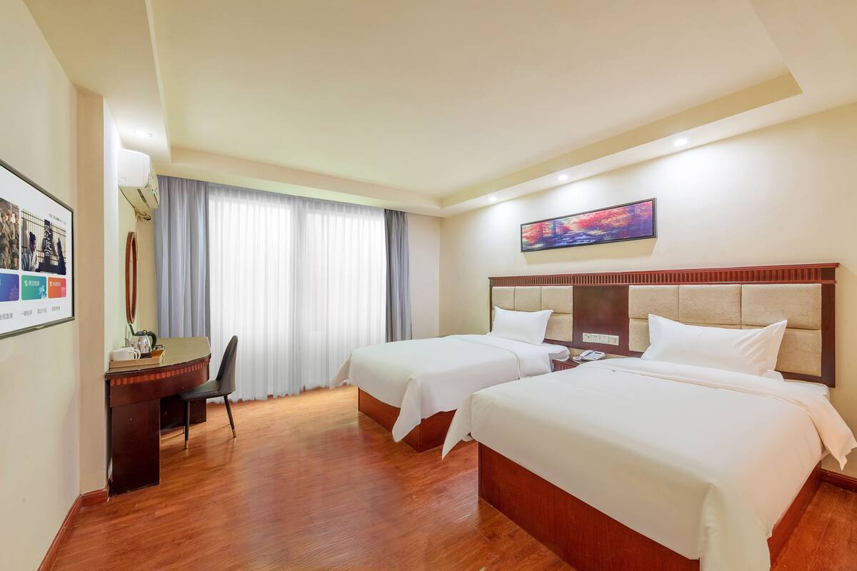 Een hotelkamer met twee bedden, een bureau en een stoel.