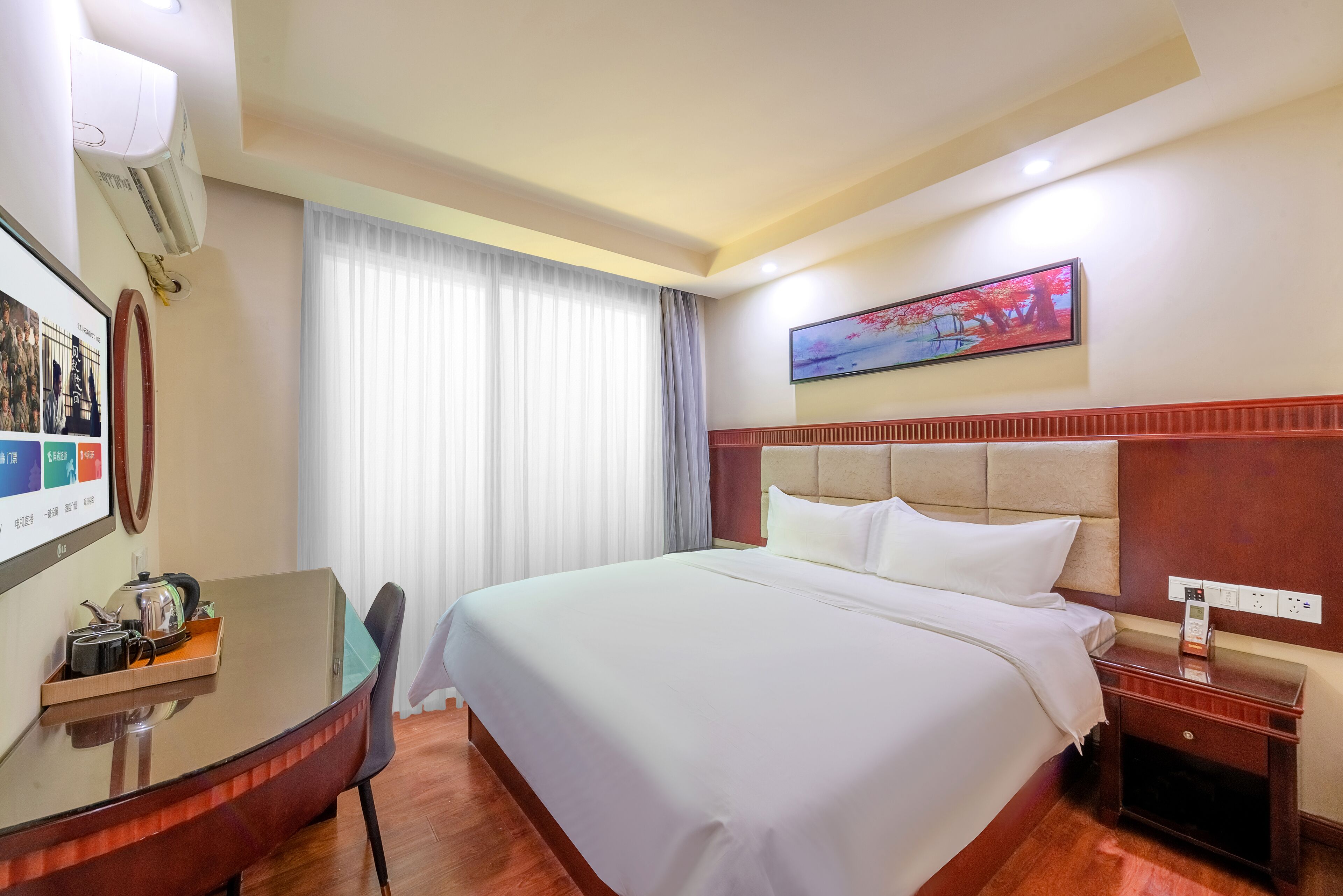 Una habitación de hotel con cama, un escritorio con silla, televisor y ventana con cortinas.