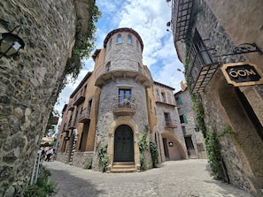 A historic stone building with a central tower, a cobblestone street, and a sign reading "OOM". - Castello di Carlo - Suite Carlo IV (Val'Quirico)