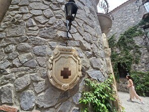 A stone wall with a coat of arms and a street lamp. - Castello di Carlo - Suite Carlo IV (Val'Quirico)