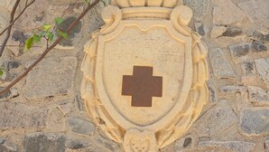 Un muro de piedra con un emblema tallado que presenta una cruz y texto.