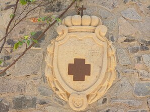Un muro de piedra con un emblema tallado que presenta una cruz y texto.