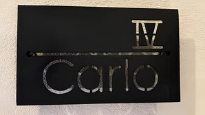 A black sign with the name "IV Carlos" in metallic letters. - Castello di Carlo - Suite Carlo IV (Val'Quirico)
