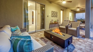 A patio area with a fire pit, outdoor seating, and a sliding glass door leading to an interior space. - Fabulous Disney Vacation Home - 8bd - Private Pool w SPA - Near to Disney (Kissimmee)