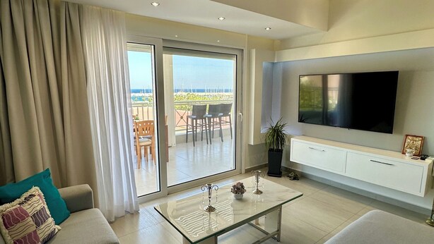 A modern living room with a large sofa, a coffee table, and a TV mounted on a white cabinet. - Luxurious Apartment with a sea view balcony in the N.Rhodes Yachting Marina Area (Rhodes)