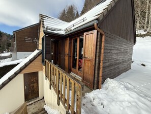 Una baita in legno con un portico, un tetto in metallo e una porta in legno.