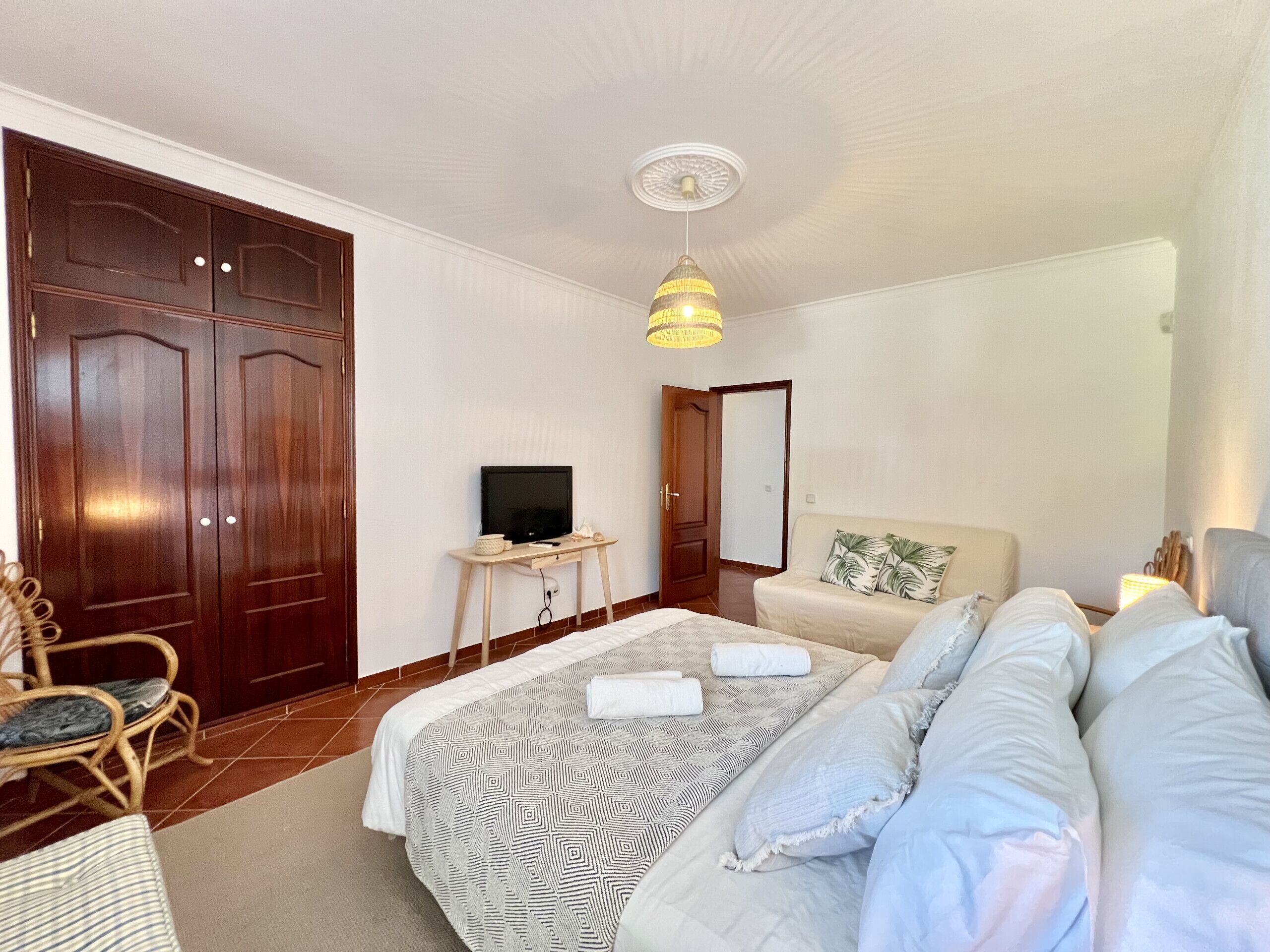 Ein Schlafzimmer mit einem Bett, einem Fernseher auf einem kleinen Tisch, einem Sofa und einem Kleiderschrank.