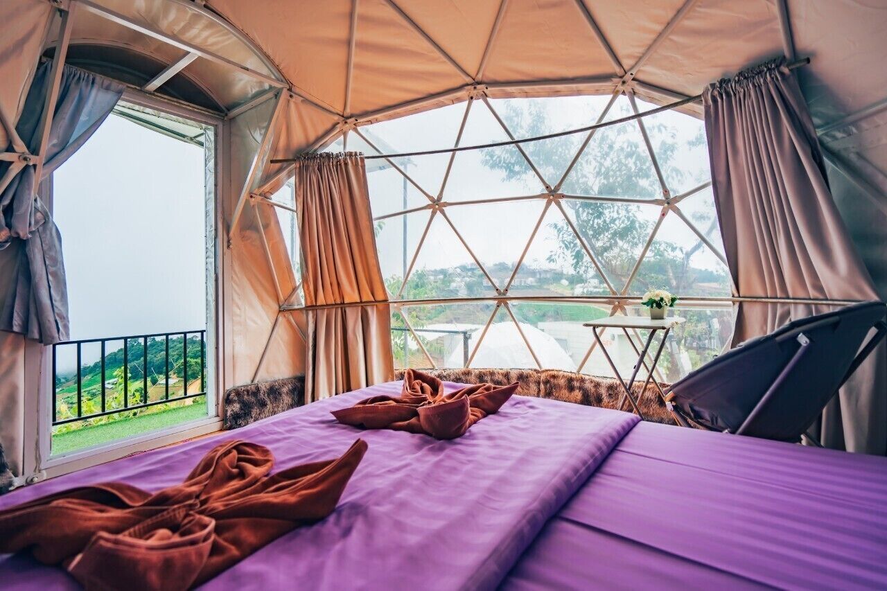 A tent-style room with a bed, a small table, and a chair.