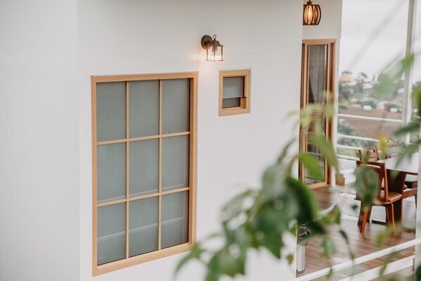 Una habitación con amplios ventanales esmerilados, un aplique pequeño en la pared y vistas al exterior.