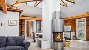 Un interior moderno con chimenea, vigas de madera, un sofá y un comedor.