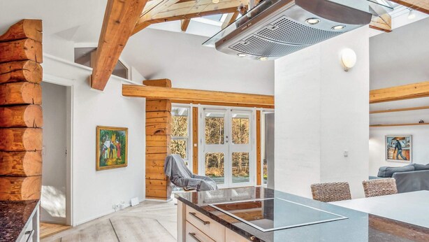 Una cocina moderna con una isla grande, vigas de madera y vistas al exterior.
