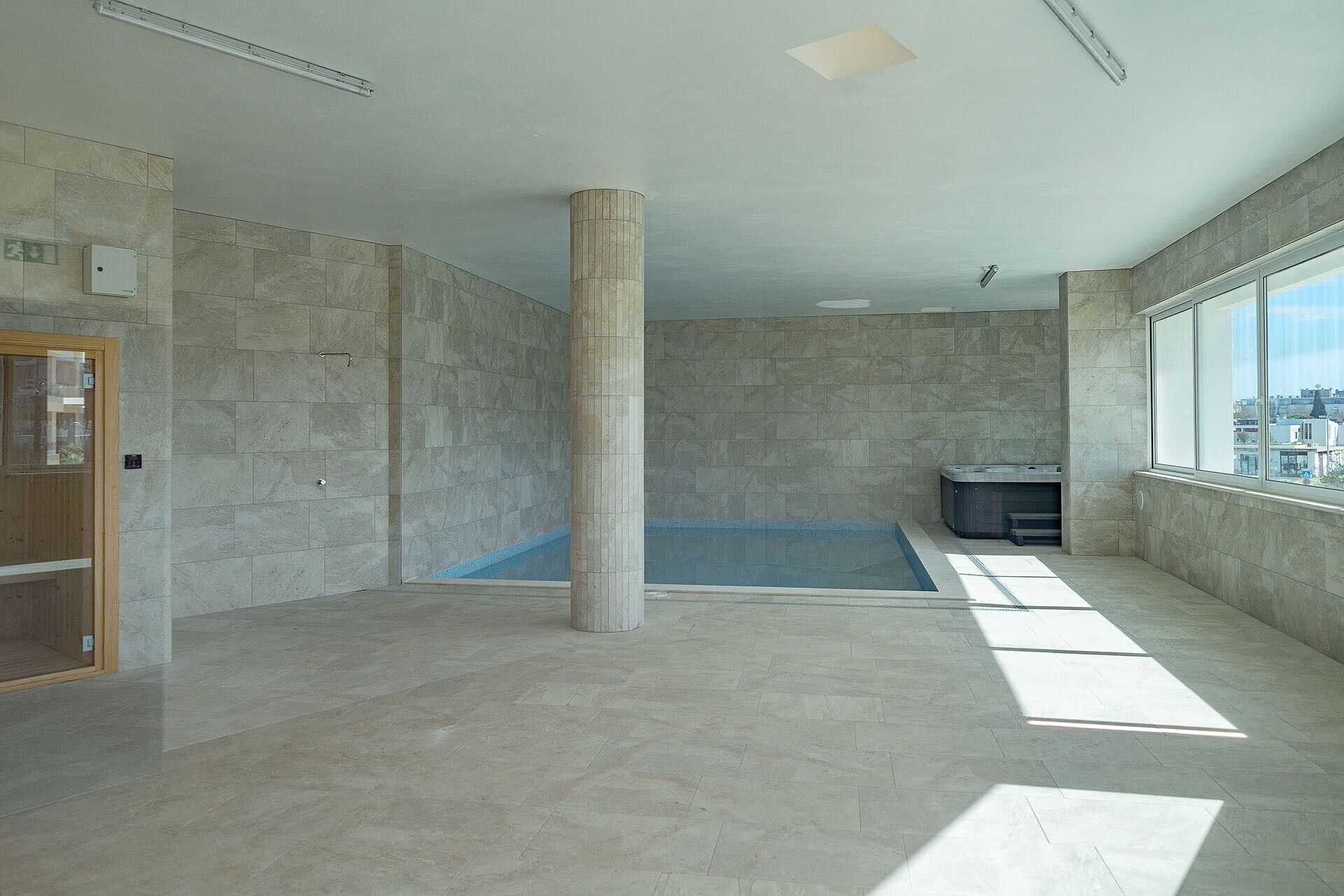 Ein geräumiges Zimmer mit einer großen Säule, einem kleinen Pool und einem Fenster mit Blick auf die Stadt.