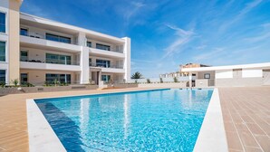 Un immeuble moderne à plusieurs étages, avec une piscine située devant.