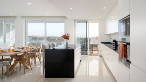 Une cuisine moderne dotée d’un îlot central, de grandes fenêtres et offrant une vue sur la ville.