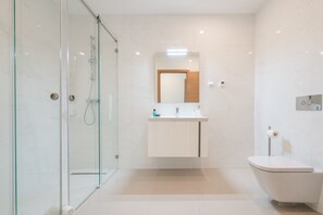 A modern bathroom with a glass-enclosed shower, a white vanity with a mirror, and a white toilet. - Lagos Marina View 4 With Pool by Homing (Lagos)