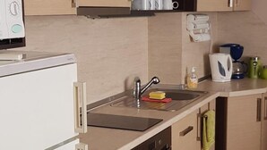 Una cocina con refrigerador, horno, pileta y alacenas.