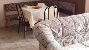 Una sala de estar con un sofá, una mesa de comedor con sillas y una lámpara colgante.