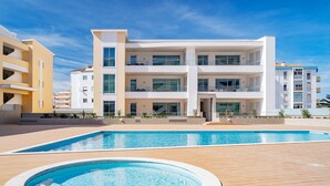 A modern multi-story hotel with a swimming pool area, including a hot tub and a rectangular pool. - Lagos Marina View 1 With Pool by Homing (Lagos)