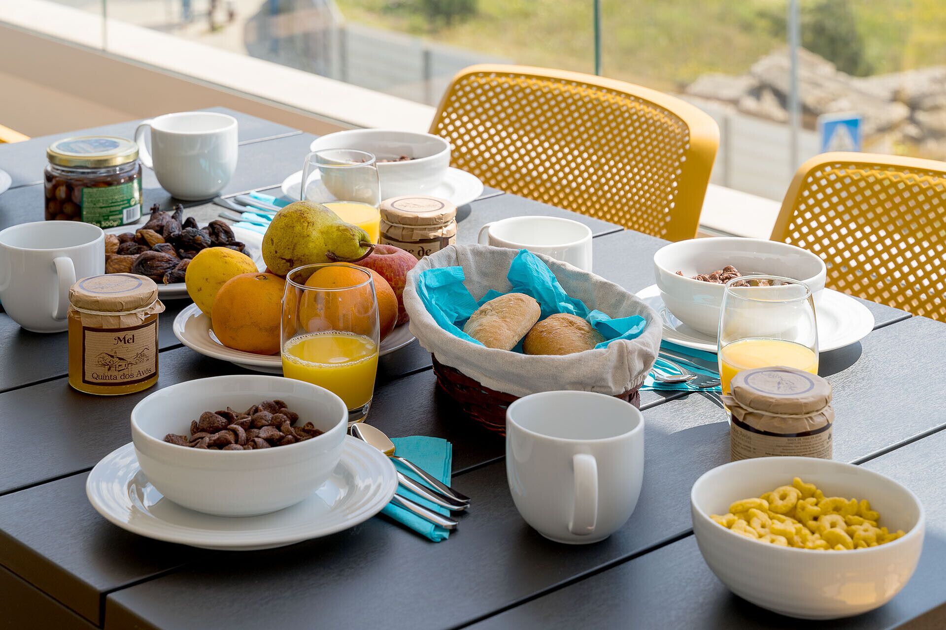 A breakfast table with various food items, including fruits, bread, cereal, and beverages.