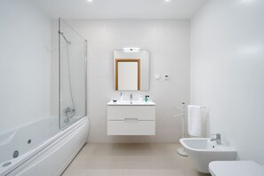Un baño moderno con ducha de vidrio, un lavamanos con espejo, un bidé y un inodoro.