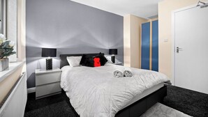 Une chambre à coucher moderne avec un lit, des tables de chevet et une armoire.