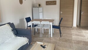 Un espacio habitable compacto con sofá, una mesa de comedor con sillas, refrigerador y microondas.