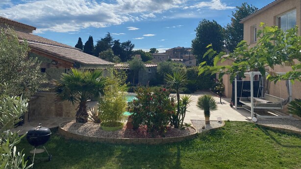 Un patio con piscina, rodeado de follaje y una pérgola.