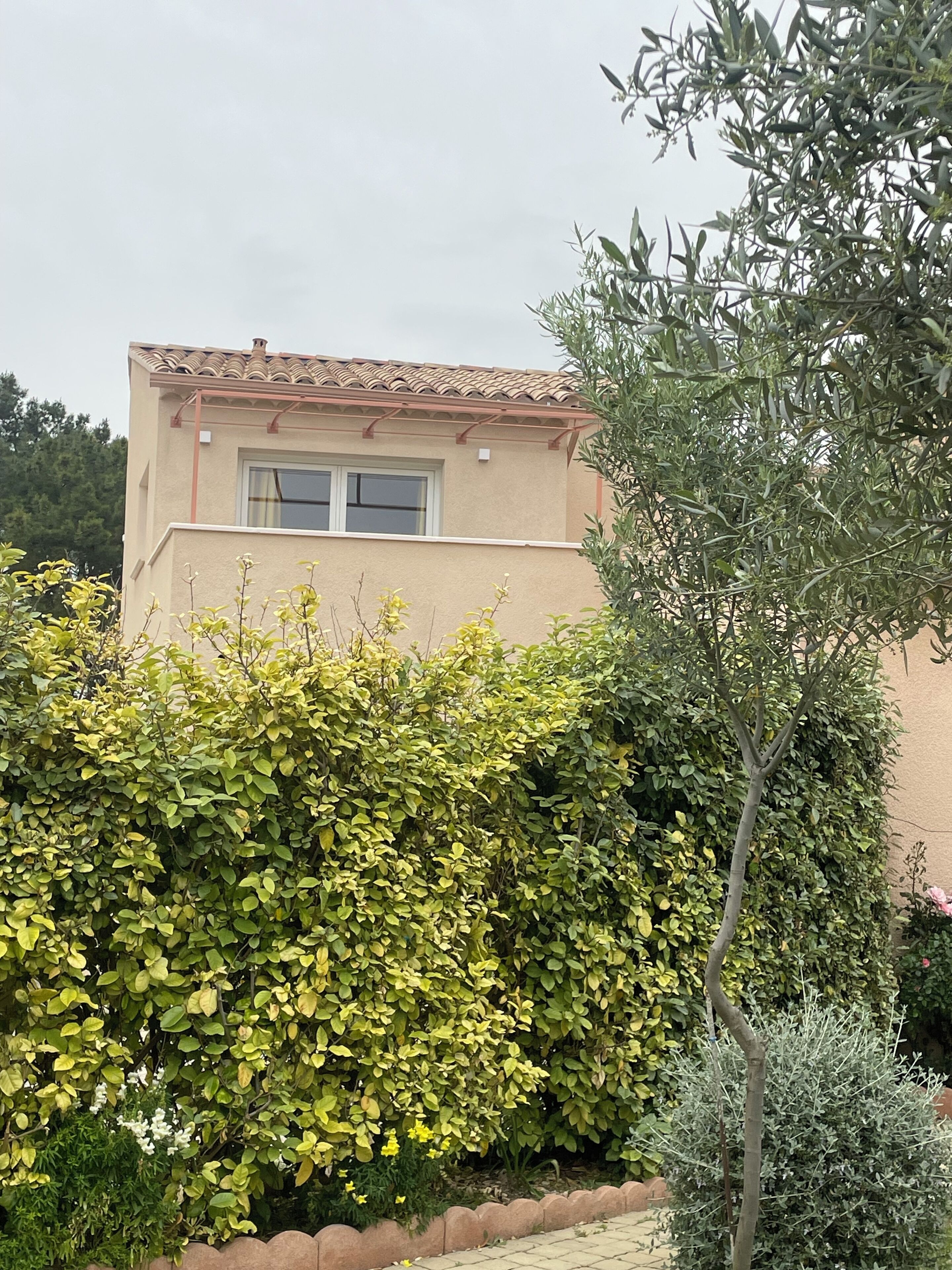 Un bâtiment à la façade beige, doté d’un toit en tuiles et d’une fenêtre.