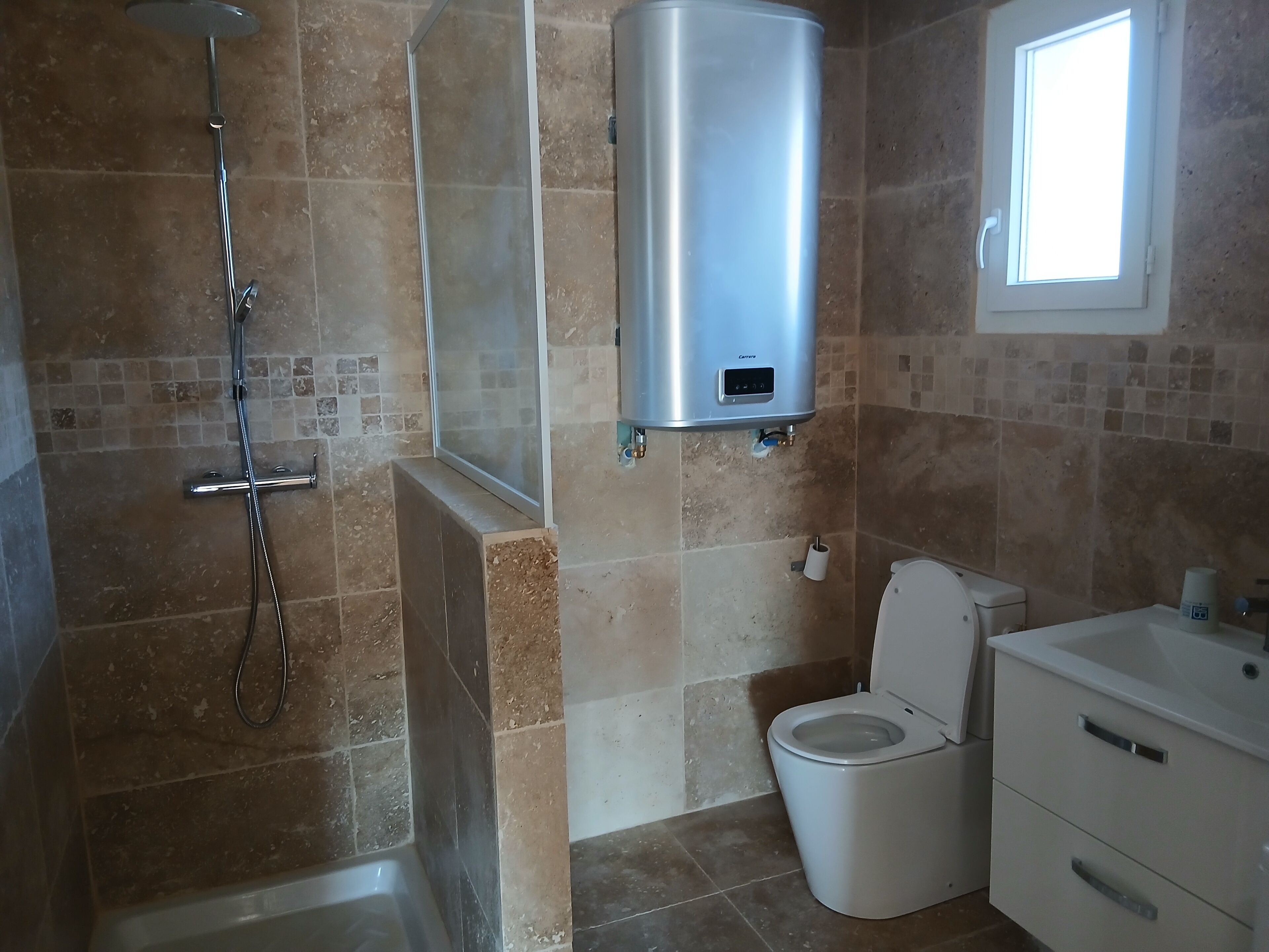A bathroom with a shower, toilet, and a built-in sink.