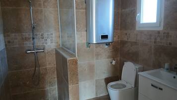 A bathroom with a shower, toilet, and a built-in sink.