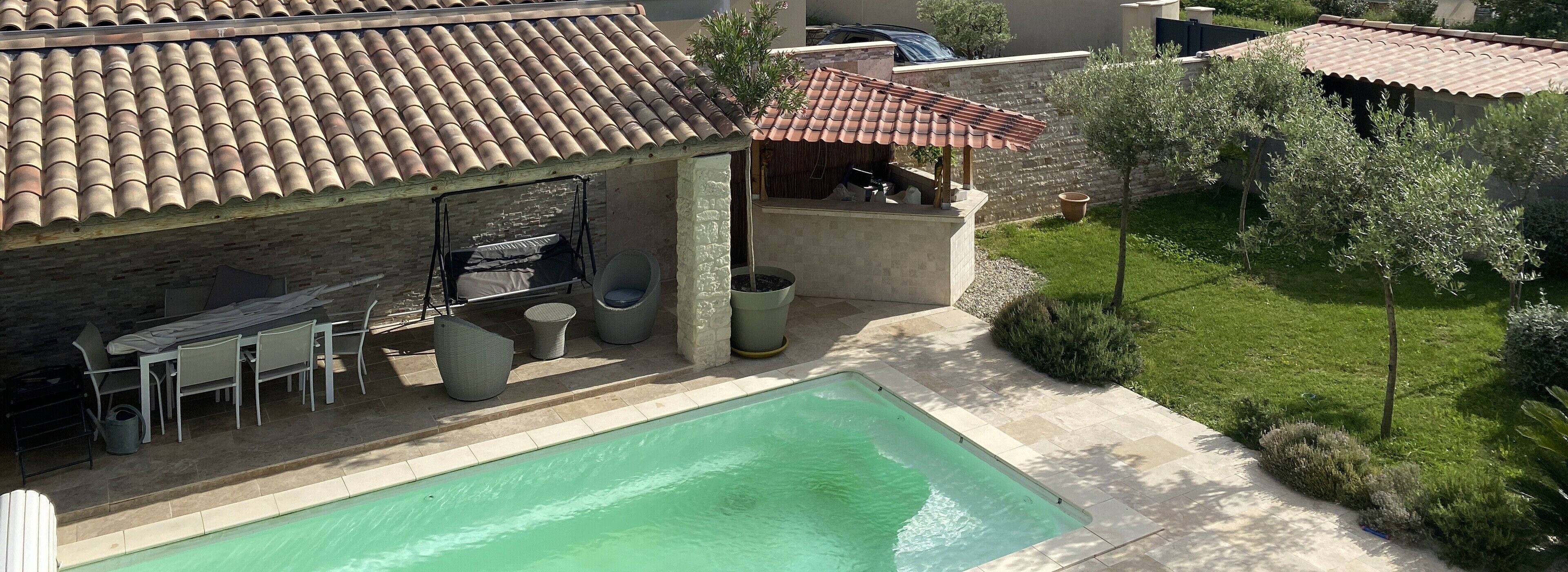 A residential property with a swimming pool, outdoor seating area, and a covered patio.