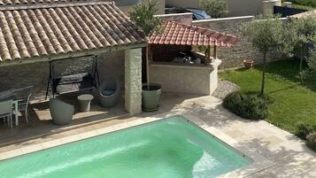 A residential property with a swimming pool, outdoor seating area, and a covered patio.