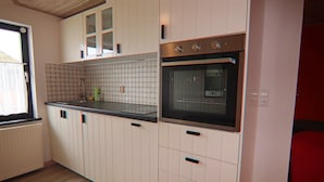 A kitchen with white cabinets, a black countertop, a built-in oven, and a window with a view. - Ferien unterm Reetdach bis zu 6 Personen (Alt Bukow OT Bantow)