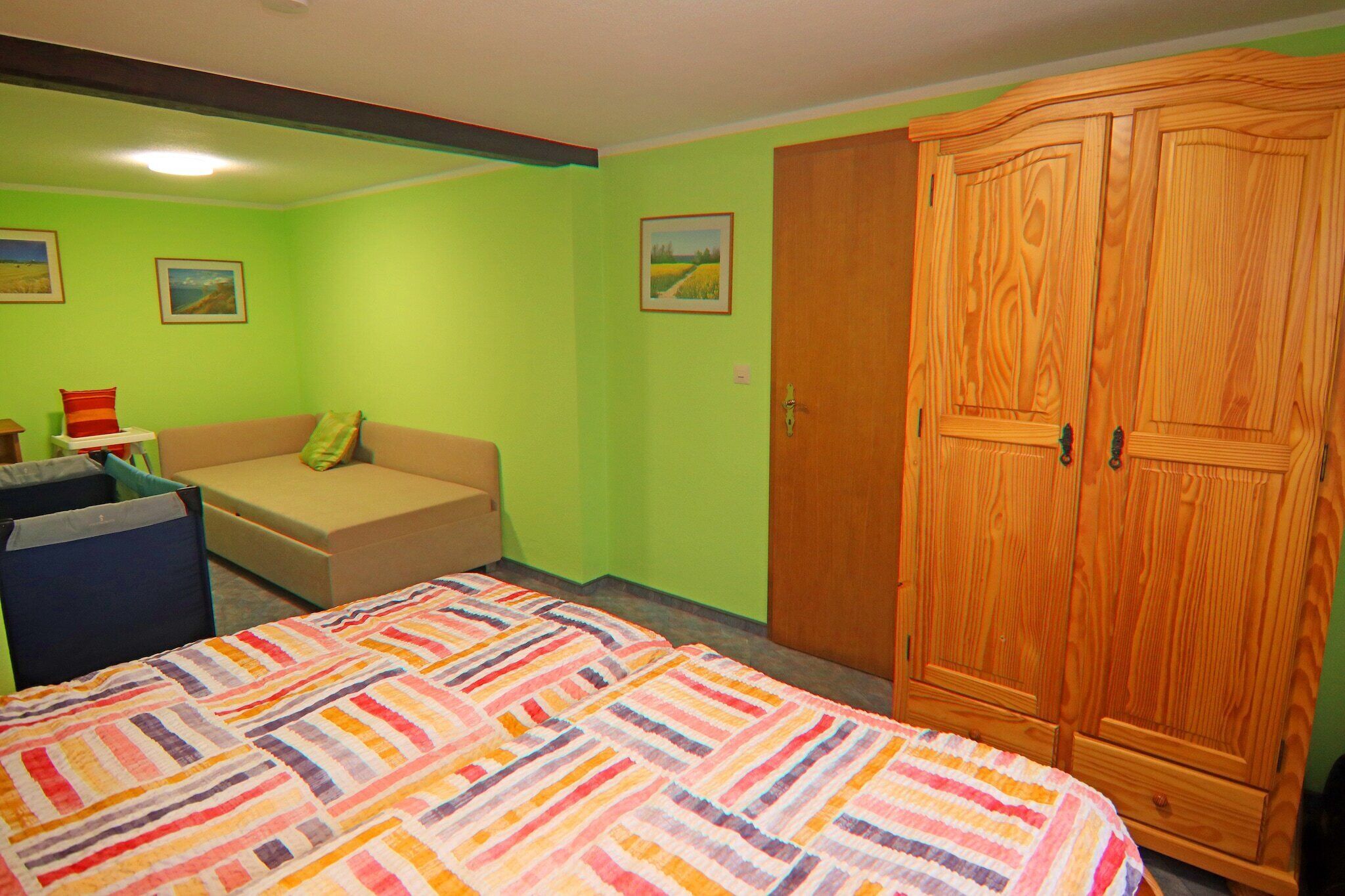 A room with a bed, a sofa, a wardrobe, and two framed pictures on the wall.