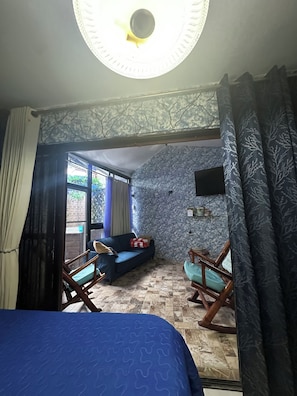 A room with a bed, a sofa, a rocking chair, and a TV on the wall.