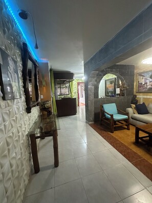 A modern living area with a sofa, a wooden chair, and a glass table. - Private jacuzzi in the center of Santo Domingo (Santo Domingo)